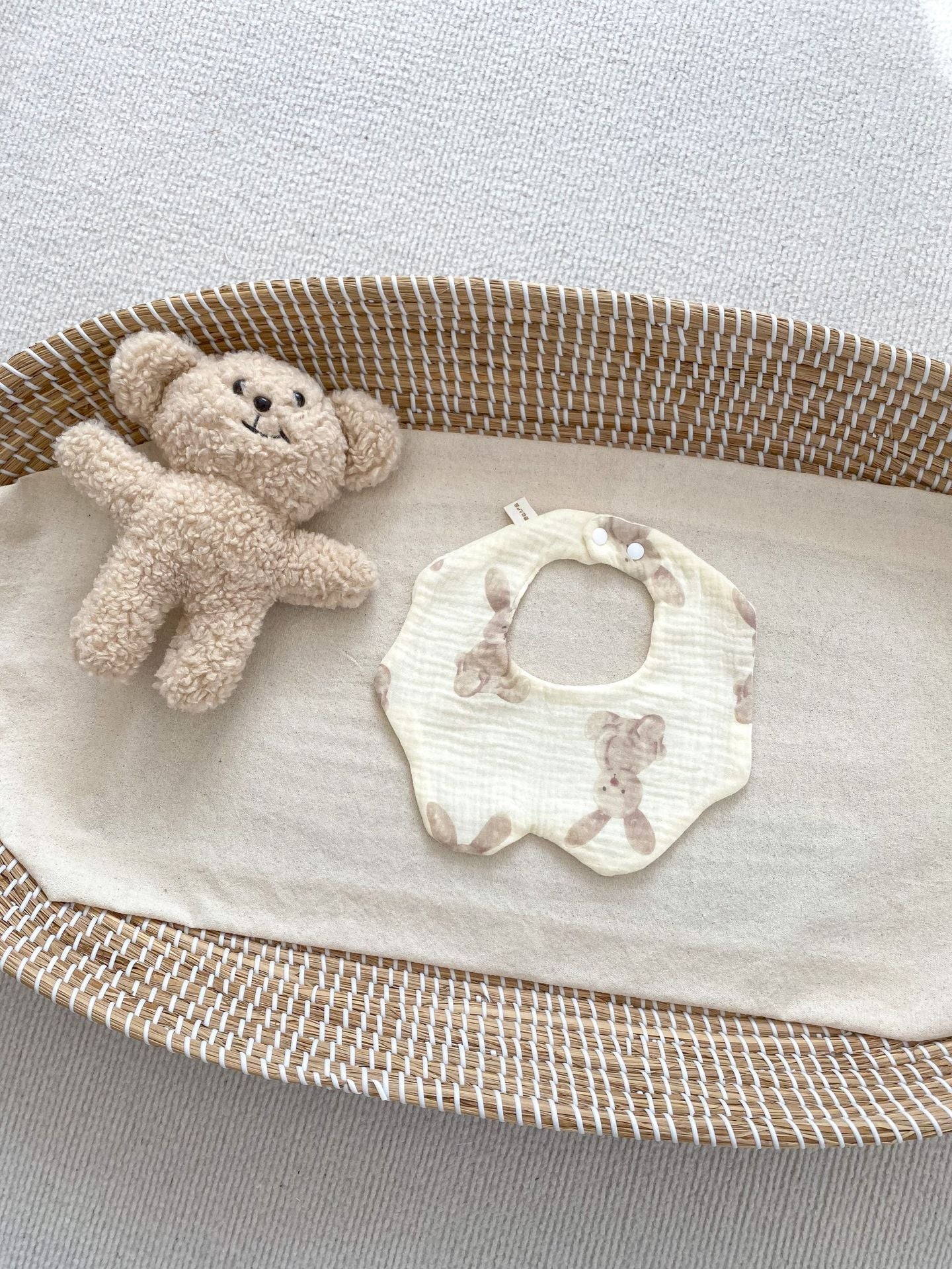 Baby bib and teddy bear on a textured surface