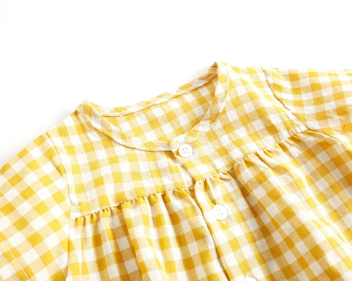 Close-up of a yellow and white checkered dress with buttons on a white background