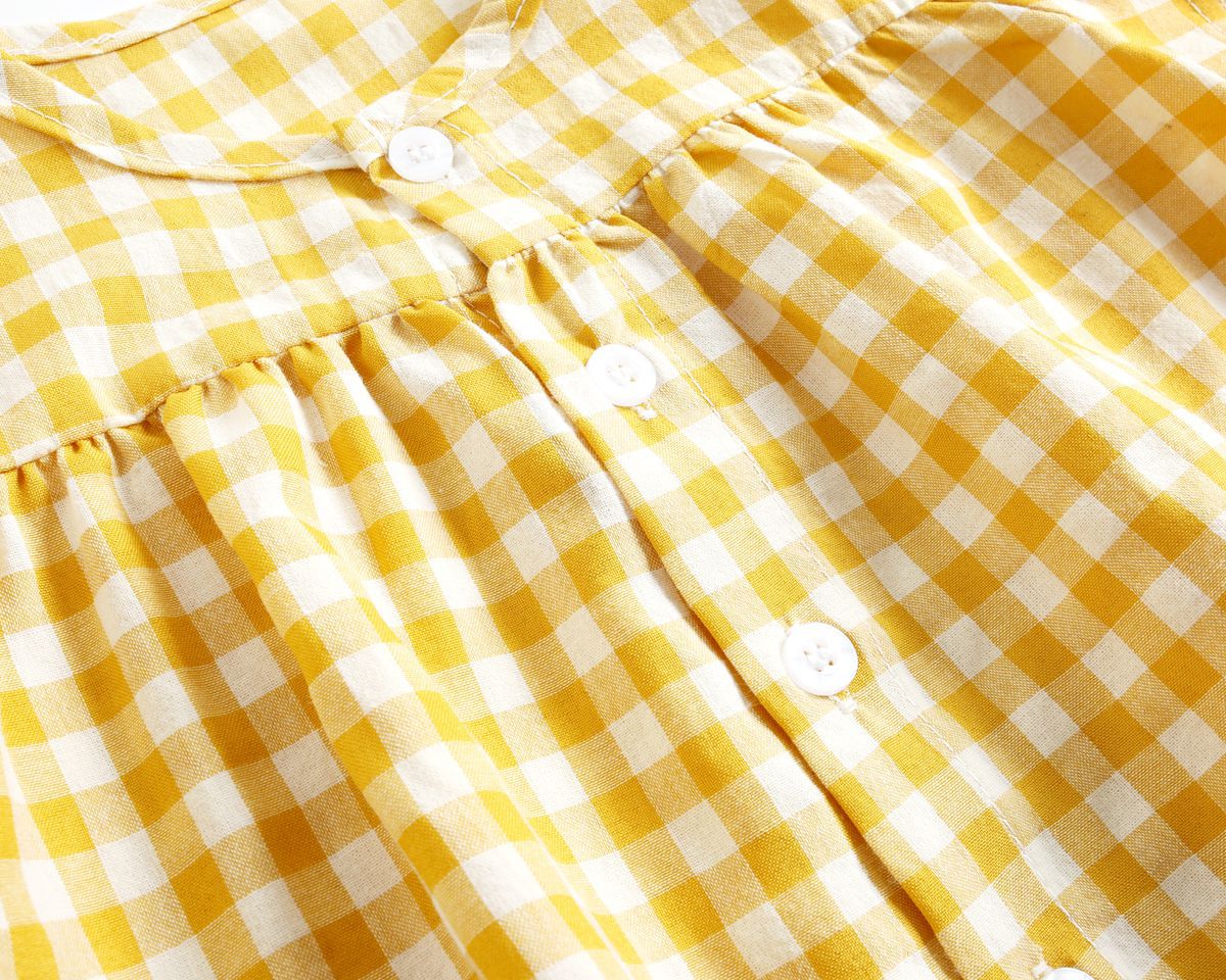 Close-up of a yellow and white checkered dress with buttons.