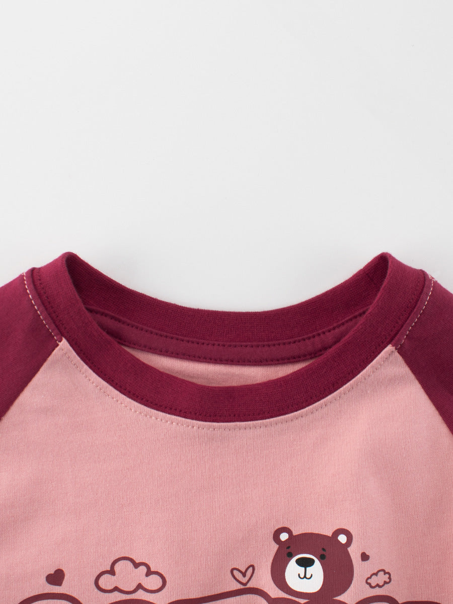 Close-up of a pink shirt with maroon sleeves and bear design on a white background