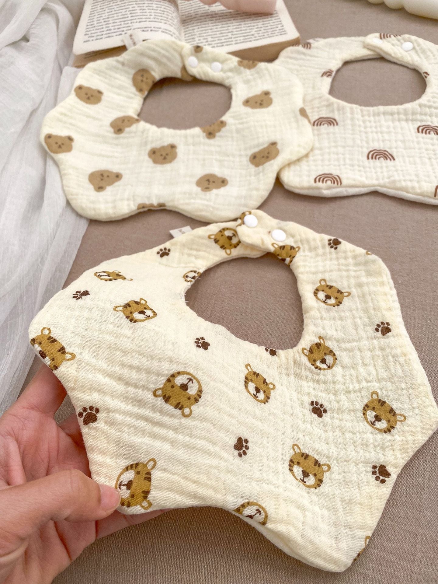 Three baby bibs with animal prints on a neutral background