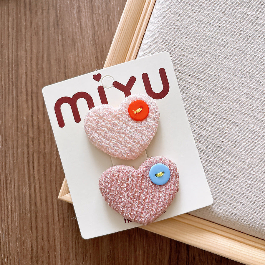 Heart-shaped hair clips with colorful buttons on a Miyu branded card.