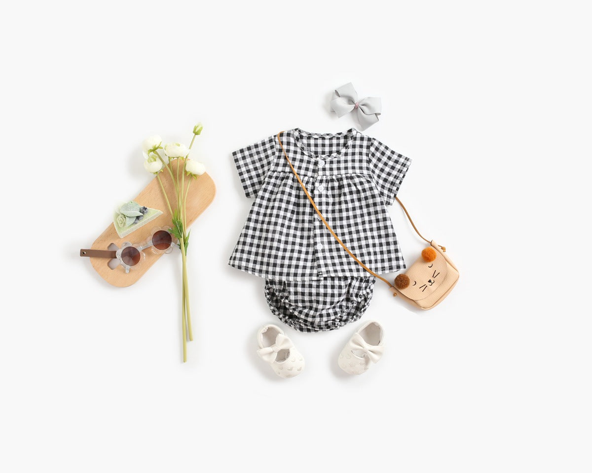 Black and white checkered baby romper with accessories on a white background