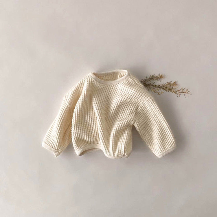 Cream-colored baby sweater on a light gray background