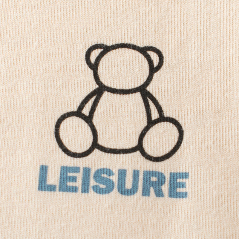 Outline of a teddy bear with the word 'LEISURE' below on beige fabric.