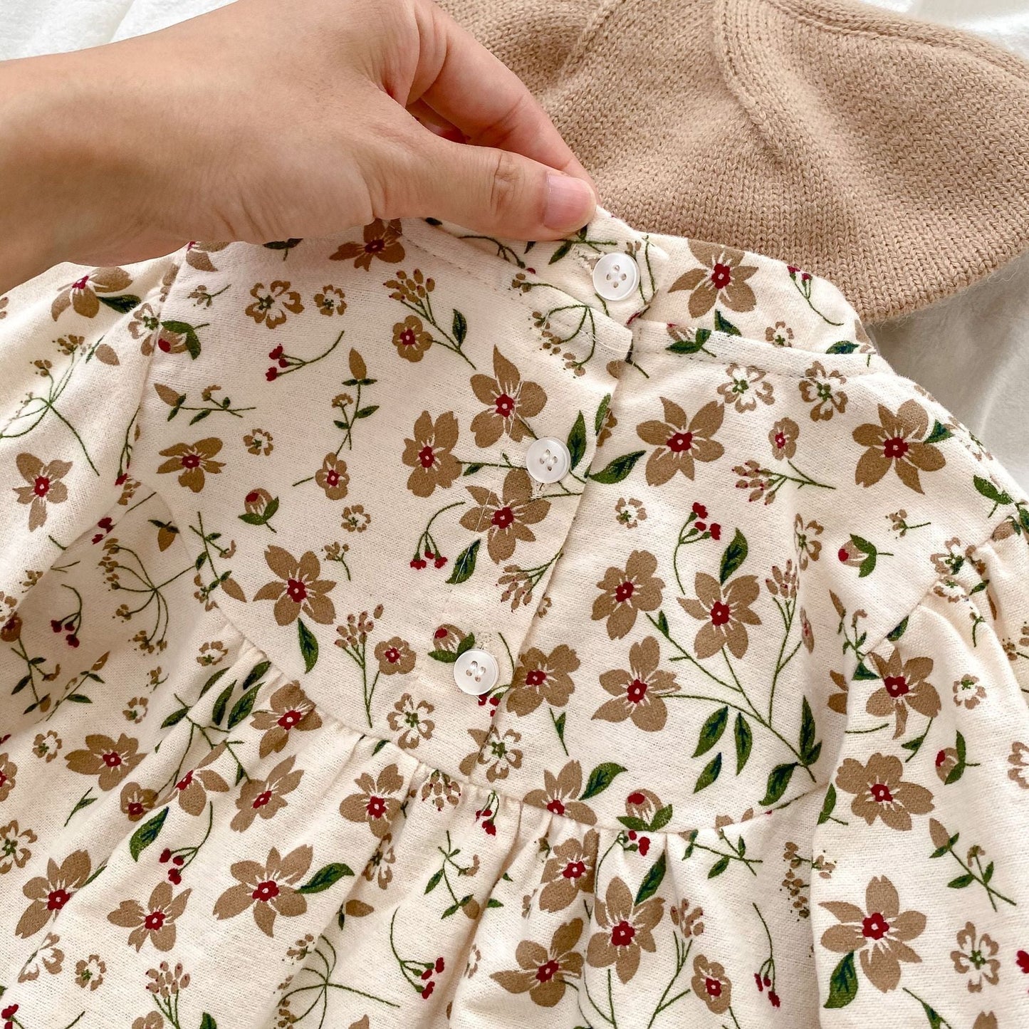 Floral-patterned fabric held by a hand with a beige background
