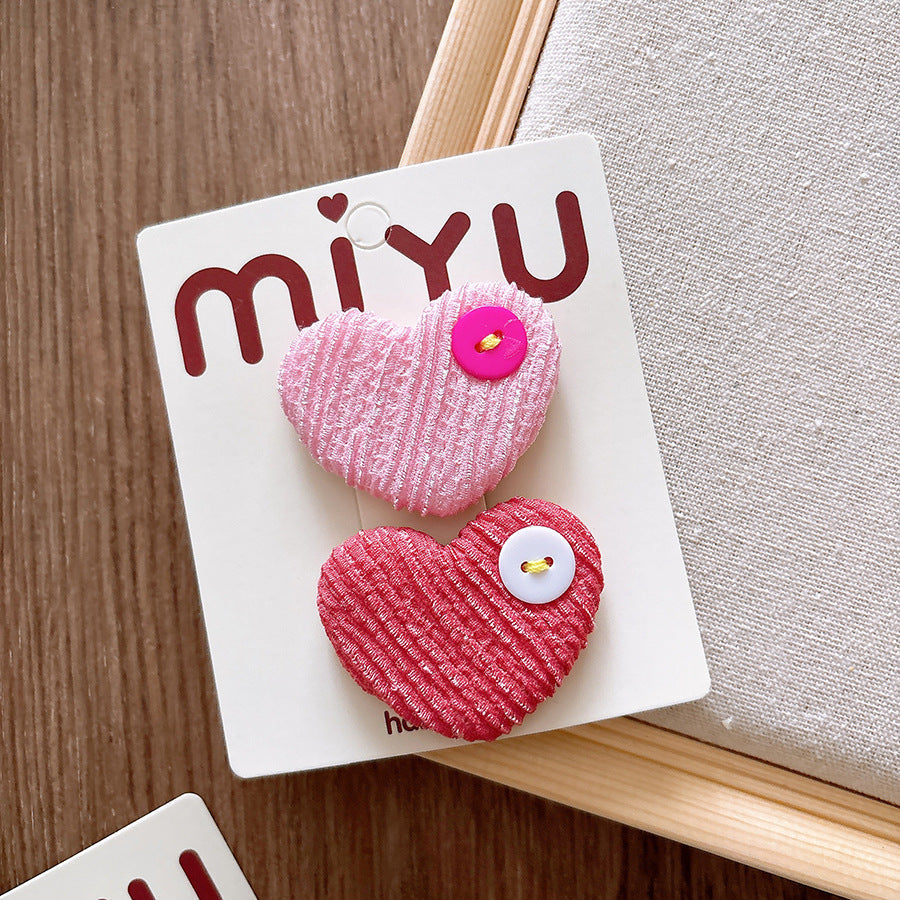 Heart-shaped hair clips on a Miyu branded card against a wooden surface.