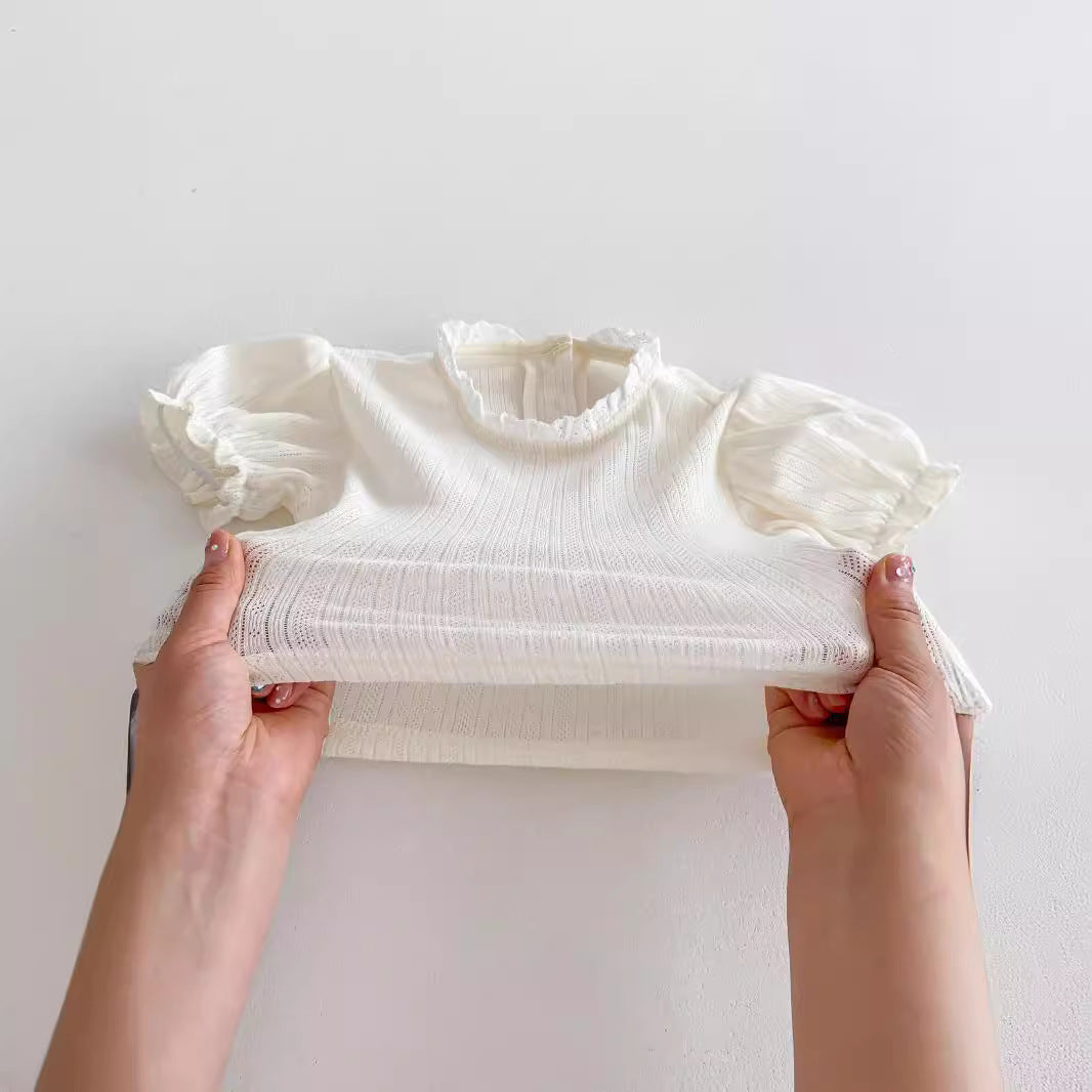 White ribbed turtleneck shirt held by hands on a light gray background