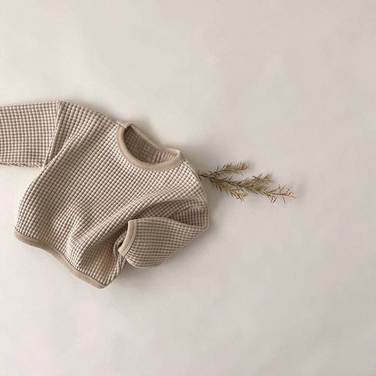 Beige baby outfit with checkered pattern on a light background