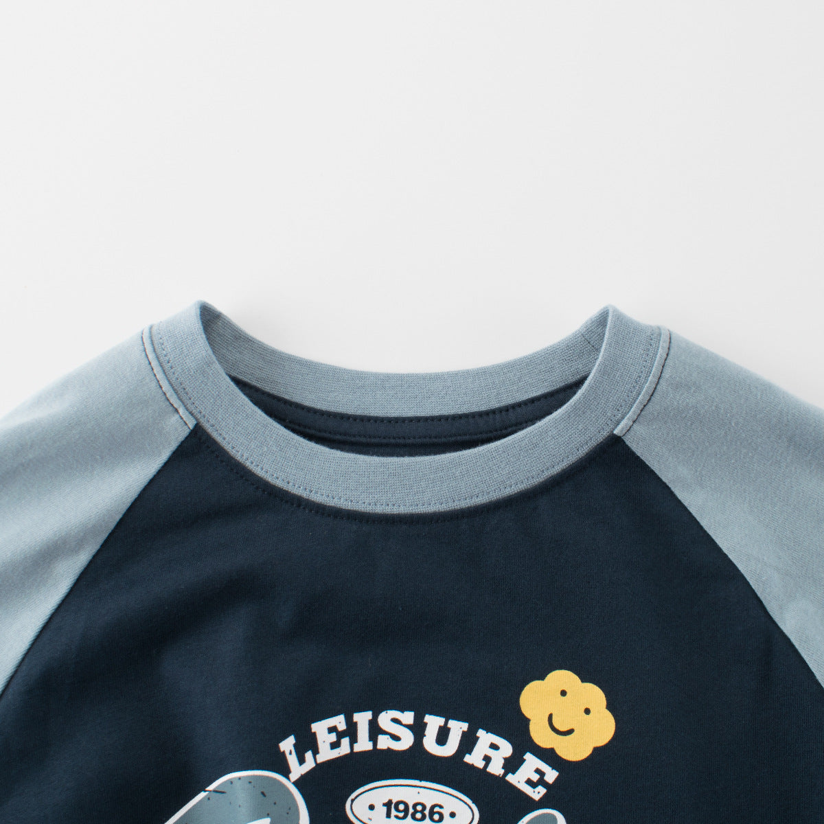 Close-up of a black and gray shirt with 'LEISURE' and a flower design on a light gray background