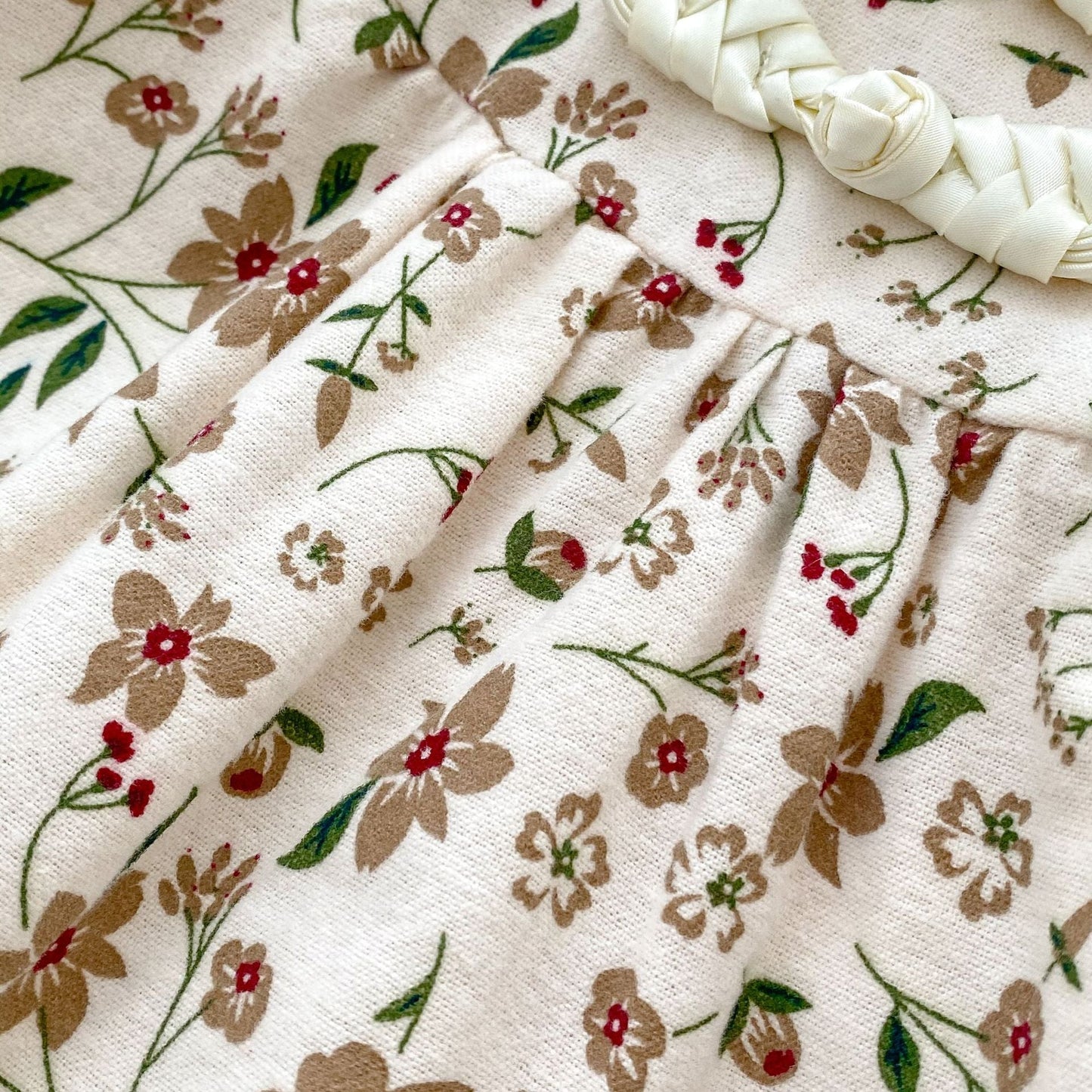 Floral patterned fabric with braided white yarn on a beige background
