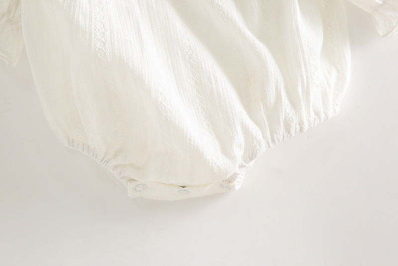 Close-up of a white fitted sheet on a bed with a light background