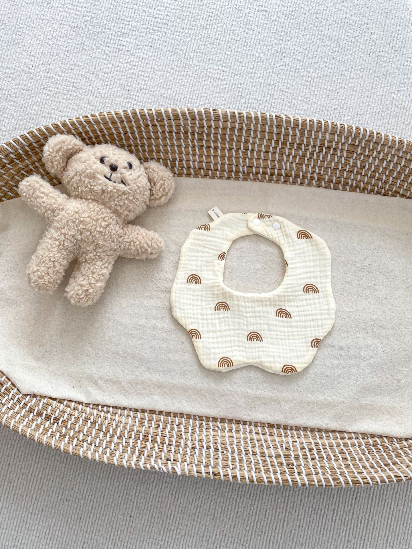 Baby bib and teddy bear on a textured surface