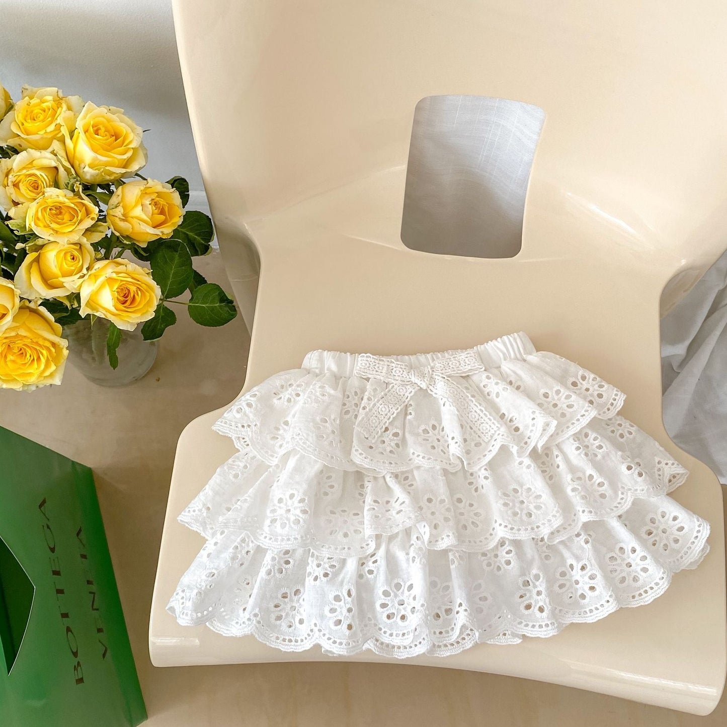 White lace skirt on a mannequin with yellow roses in the background
