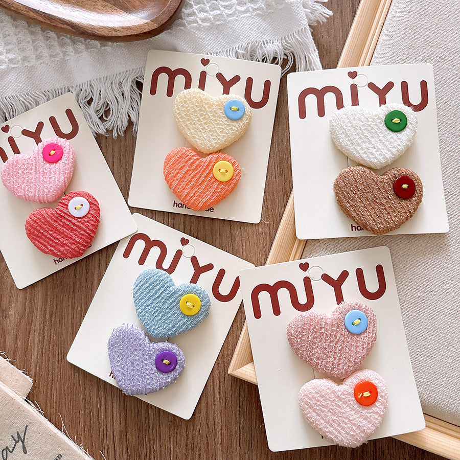 Colorful heart-shaped brooches on 'miyu' branded cards on a wooden surface.