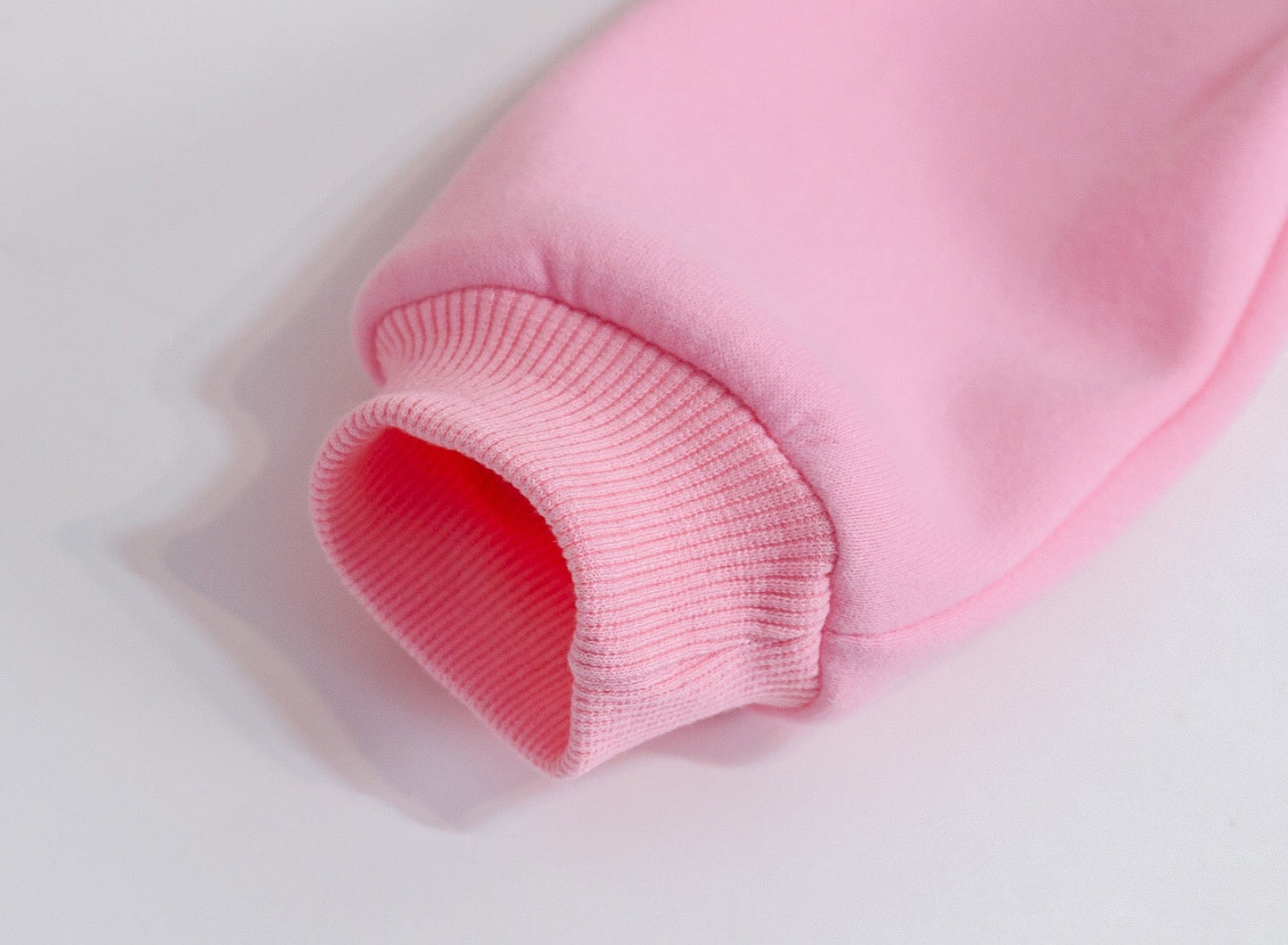 Close-up of a pink fabric with a textured pattern on a light gray background