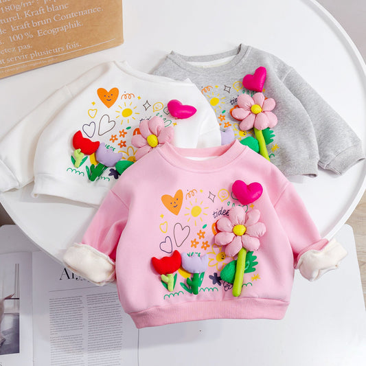 Children's pink hoodie with floral and heart designs on a white surface.