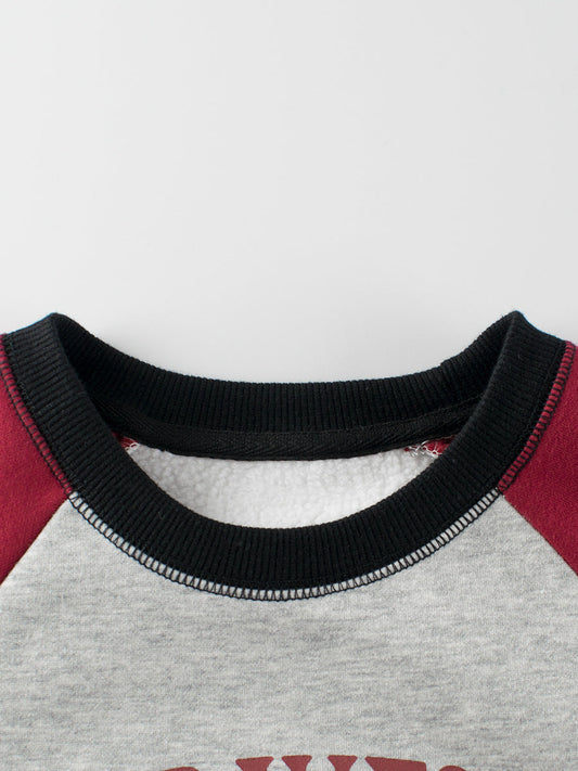 Close-up of a sweater collar with black trim on a gray and red garment.