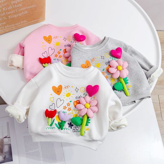 Three children's sweatshirts with floral designs on a white surface.