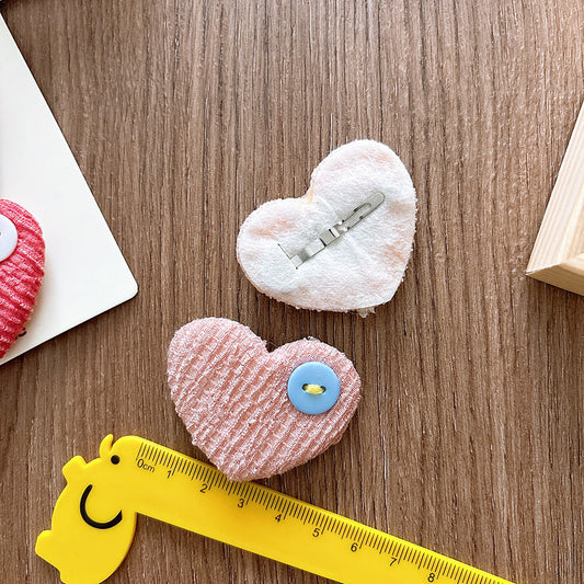 Heart-shaped plush toys with buttons on a wooden surface, accompanied by a yellow ruler for scale.