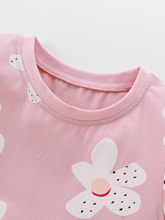 Close-up of a pink shirt with a white flower design on a light gray background