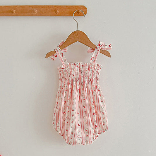 Pink floral baby romper on a wooden hanger against a plain background
