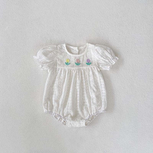White baby romper with floral embroidery on a light gray background