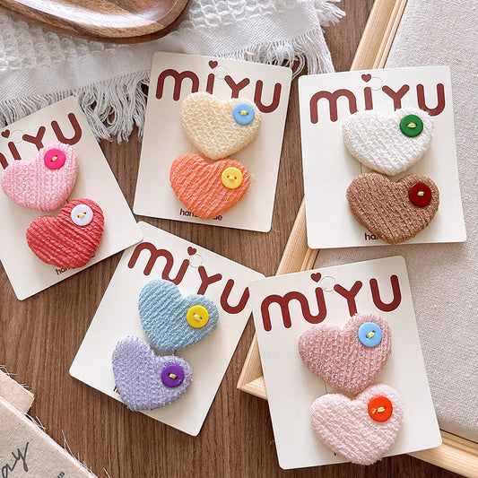 Colorful heart-shaped brooches on 'miyu' branded cards on a wooden surface.